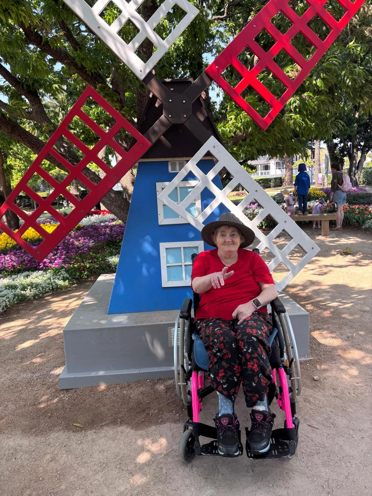 A participant in her wheelchair beside the windmill display in the gardens