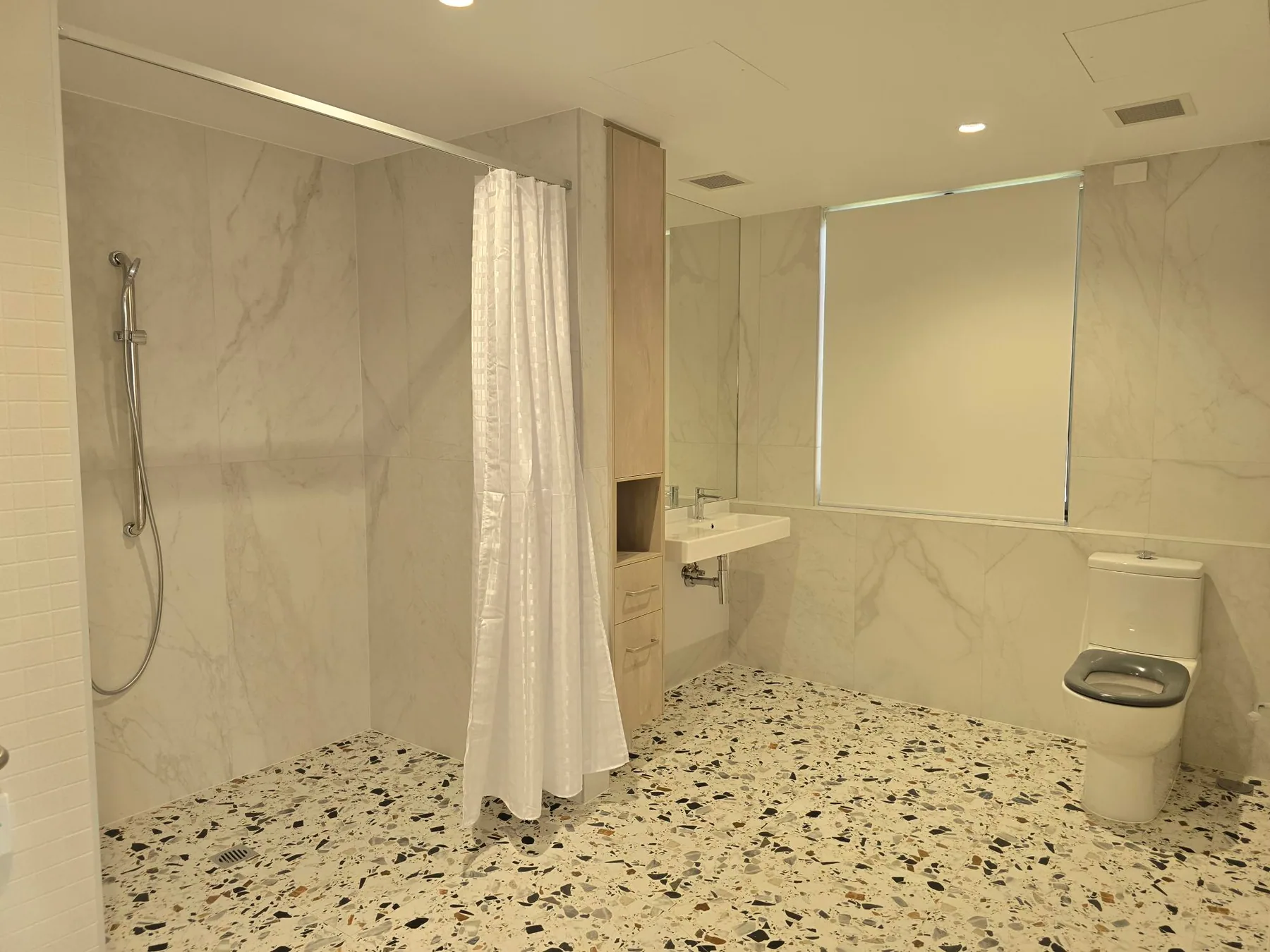 A resident's own bathroom - curtained roll-in shower and a full turning circle